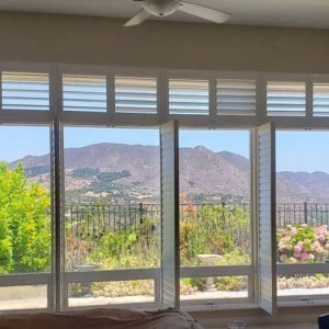 Photo of a window looking outside the home with interior shutters